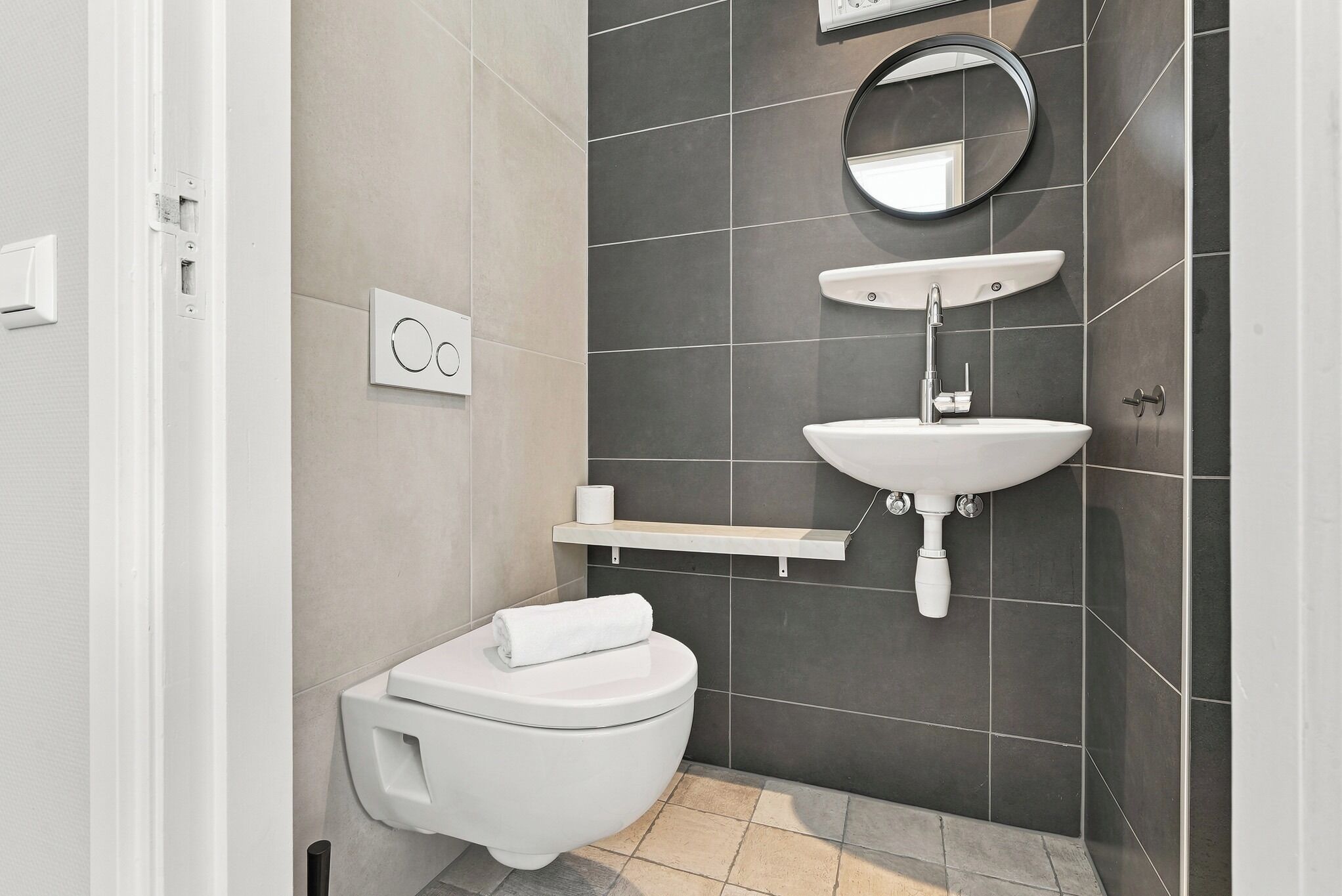 A modern bathroom with a toilet, sink, and mirror.