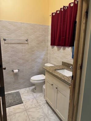 Un bagno con toilette, lavabo, mobile lavabo, tenda da doccia e porta asciugamani.
