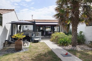 A patio area with outdoor furniture, a grill, and a palm tree. - Holiday Home “Lilas NO” with Terrace, Private Garden, and Wi-Fi (Barbâtre)