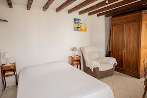 Ein Schlafzimmer mit Bett, Nachttisch, Stuhl, Kleiderschrank und einem Gemälde an der Wand.