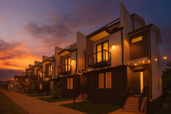A row of modern two-story townhouses with balconies, front steps, and string lights. - 2 Units, Sleeps 24  Nashville's Best Location (Nashville)