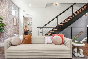 A modern living room with a sofa, a staircase, and a patterned wall. - 2 Units, Sleeps 24  Nashville's Best Location (Nashville)