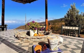 Ein Tisch mit einer Kaffeetasse, einem Obstkorb und einer Blumenvase.