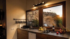 Une cuisine avec un mur en pierre, un évier, une cuisinière et une bouteille de vin.