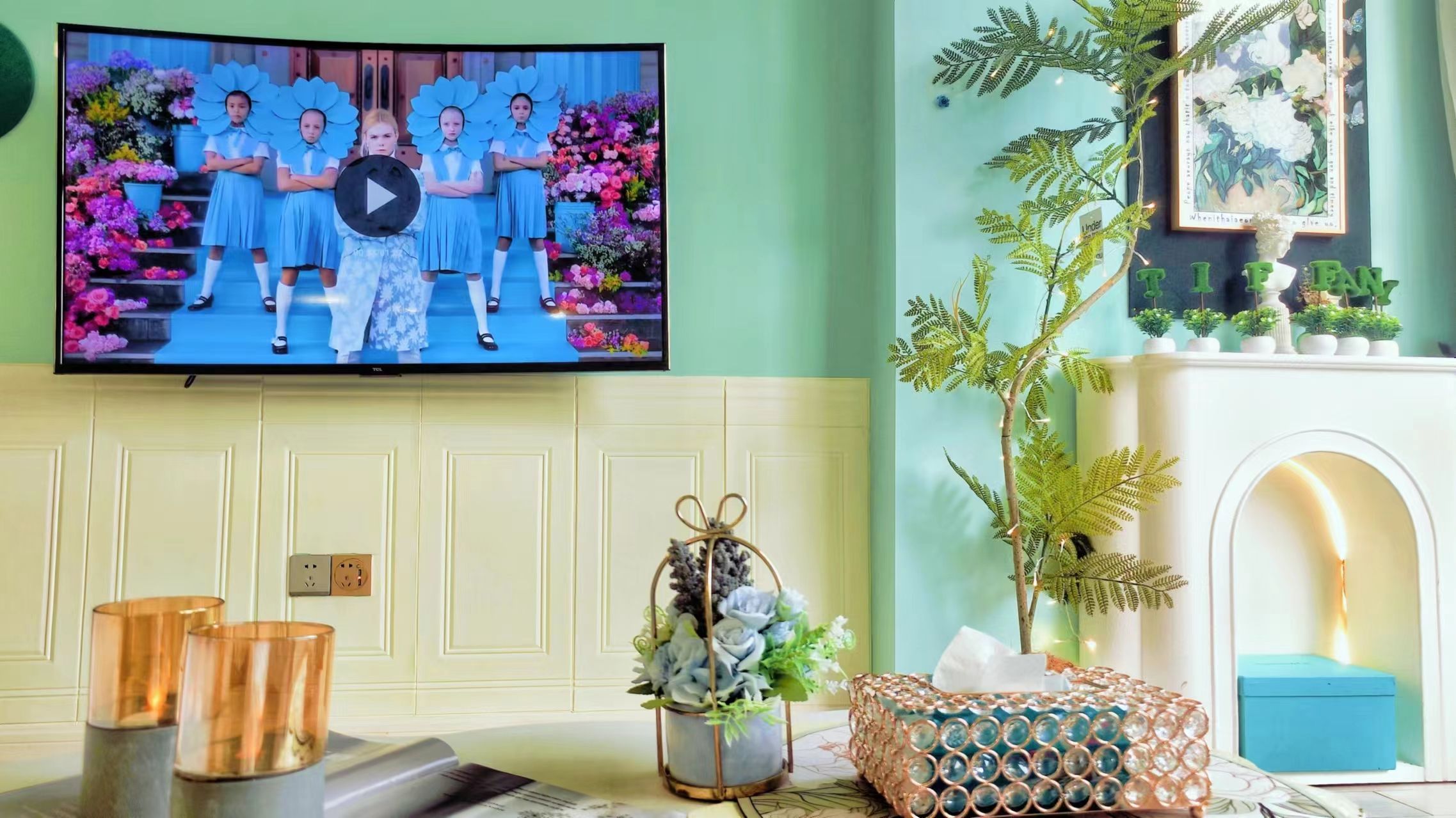 Ein Wohnzimmer mit Fernseher, Kamin, einer Pflanze und einem dekorativen Gegenstand auf dem Kaminbrett.