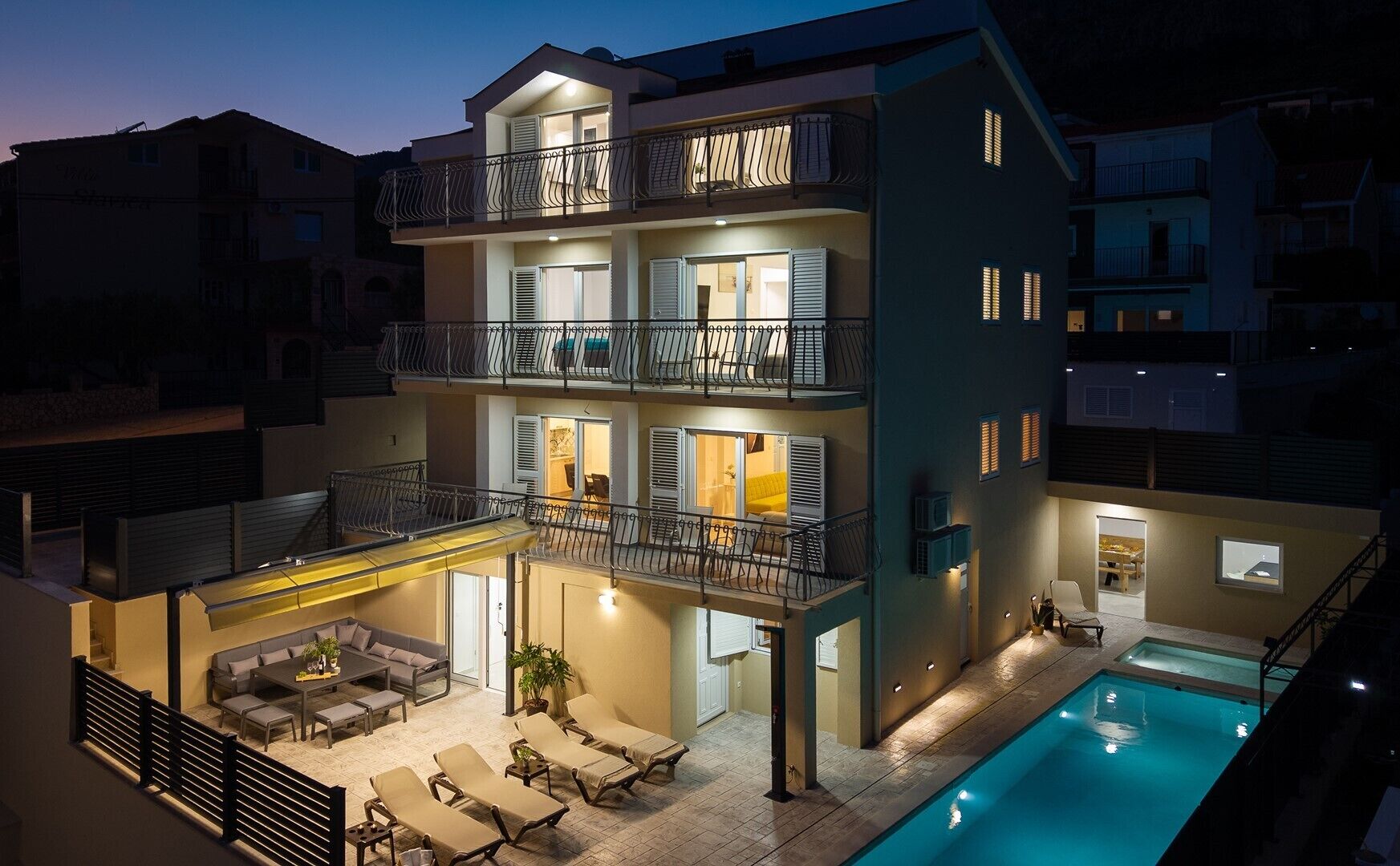 A multi-story building with a pool, outdoor seating, and balconies.