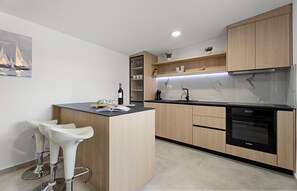 A modern kitchen with a central island, bar stools, a built-in oven, and a marble backsplash. - Seaview Villa Diamond, 7-bedroom villa Just 500 Meters from the Beach (Dugi Rat)