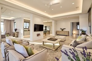 A spacious living room with a sofa set, a coffee table, and a flat-screen TV. - Luxury Villa Sapphire (Mykonos)