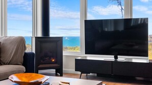 Ein Wohnzimmer mit Kamin, Fernseher und Meerblick.