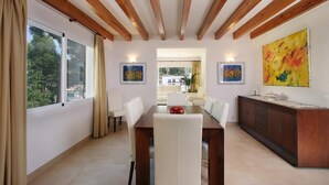 Zona pranzo con soffitto in legno, tavolo, sedie, un armadietto e opere d'arte alle pareti.