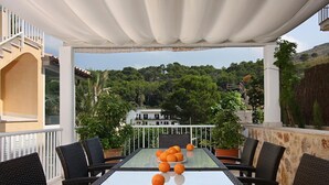 Una terrazza esterna con tavolo, sedie e vista su una collina.
