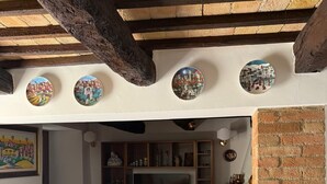 A living room with a white sofa, red chair, TV, and decorative plates on the wall. - Terrace of Collepino | Panoramic Holiday Home in Umbria (Collepino)