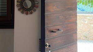 Una porta de fusta amb una nansa i una clau, flanquejada per dos ornaments murals.