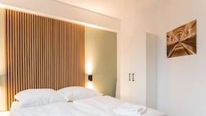 Ett modernt hotellrum med en säng, en väggpanel i trä, en vägglampa och en inramad tavla.