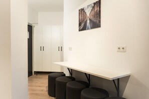 Eine moderne Küche mit weißer Arbeitsplatte, schwarzen Barhocker und Blick auf die Straße durch das Fenster.