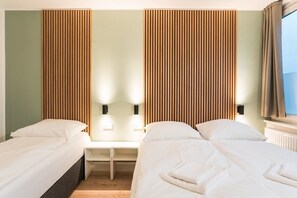 Camera d'albergo con due letti, un comodino e una lampada a parete.