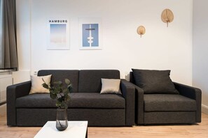 Ein modernes Wohnzimmer mit einem grauen Sofa, einem weißen Couchtisch und zwei gerahmten Bildern an der Wand.