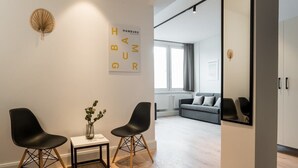 A modern room with two black chairs, a small table with a vase, and a large mirror on the wall.