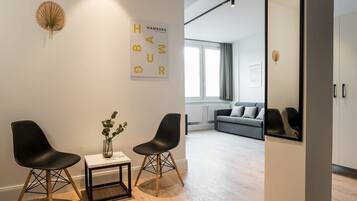 Ein modernes Zimmer mit zwei schwarzen Stühlen, einem kleinen Tisch mit einer Vase und einem großen Spiegel an der Wand.