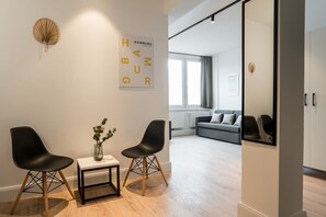 Ein modernes Zimmer mit zwei schwarzen Stühlen, einem kleinen Tisch mit einer Vase und einem großen Spiegel an der Wand.