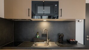 A modern kitchen with a built-in microwave, a stainless steel sink, a coffee machine, and a kettle.