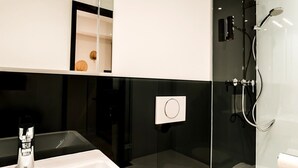 A modern bathroom with a white sink, a mirror, a glass shower enclosure, and a toilet. - Standard Apartment - Homaris Apartments Hamburg Altona (Hamburg)