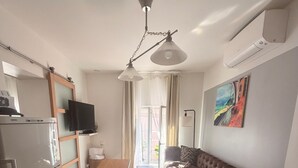 Et moderne køkken med et køleskab, et fladskærms-tv og et spiseområde med bord og stole.