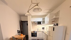 Et moderne køkken med hvide skabe, en mikrobølgeovn og et køleskab.