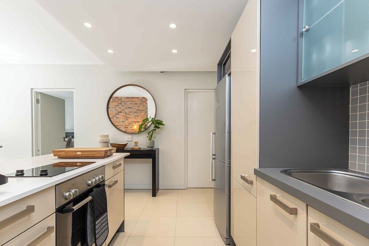 A modern kitchen with a built-in oven, a refrigerator, and a sink.