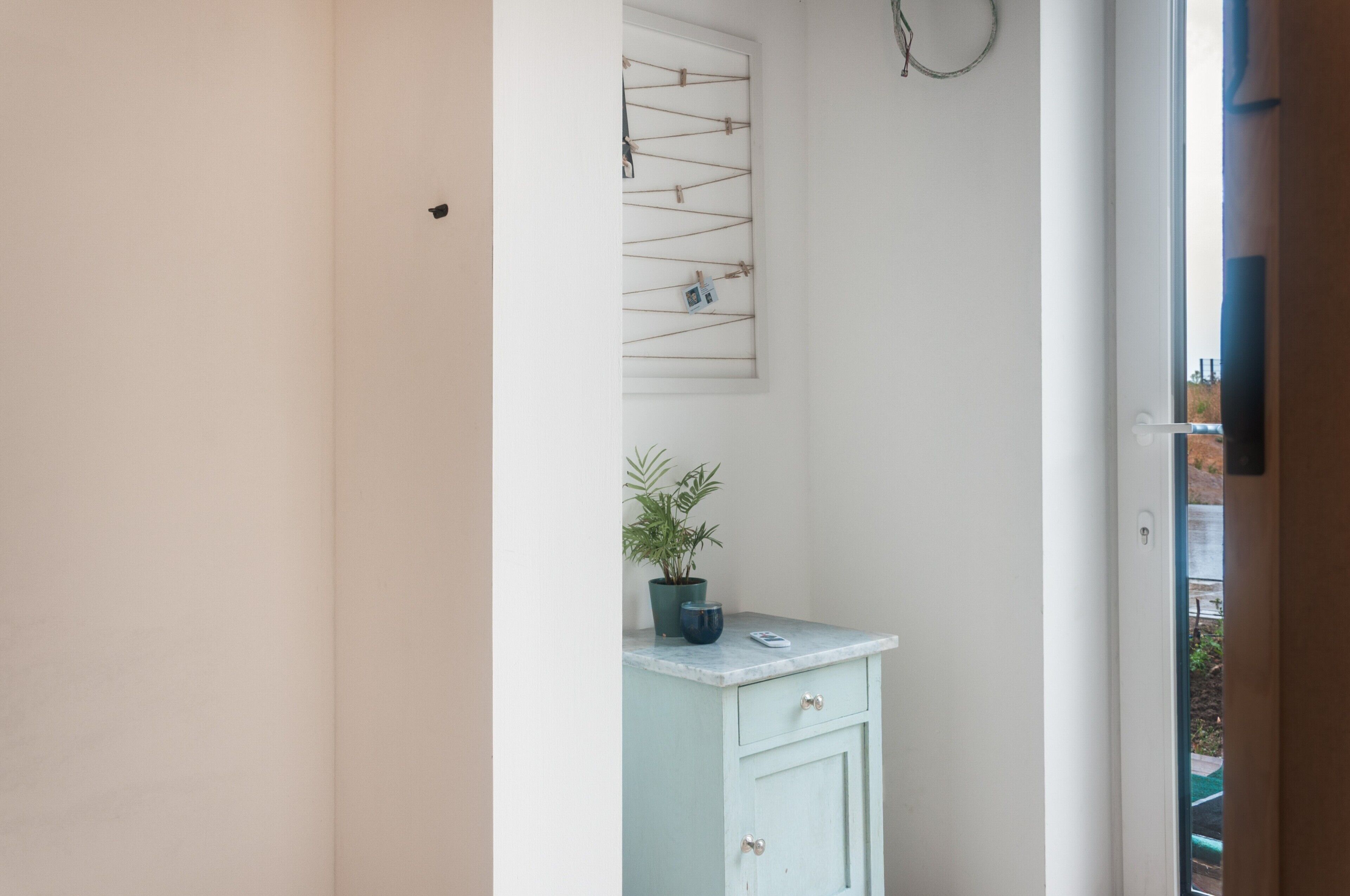 Une salle de bain avec une porte blanche, un meuble bleu clair, une plante en pot et un porte-serviettes fixé au mur.