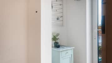 Une salle de bain avec une porte blanche, un meuble bleu clair, une plante en pot et un porte-serviettes fixé au mur.
