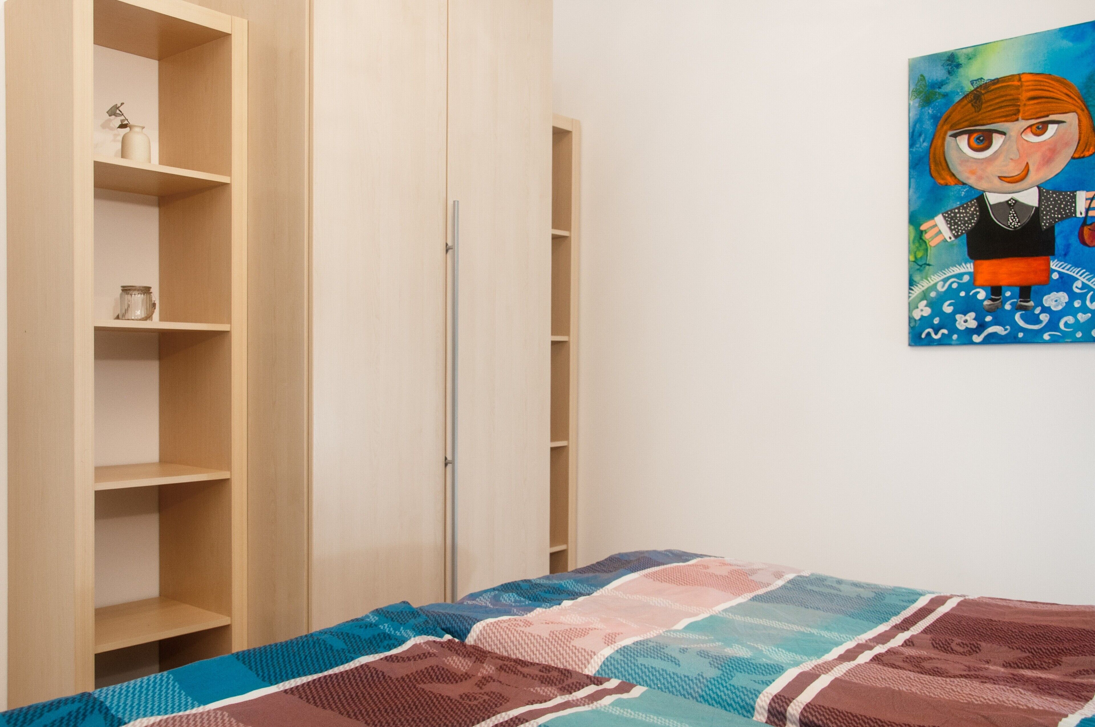Une chambre à coucher avec un lit, une armoire et un tableau accroché au mur.