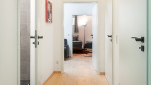 A hallway with a bed, a lamp, and a door.