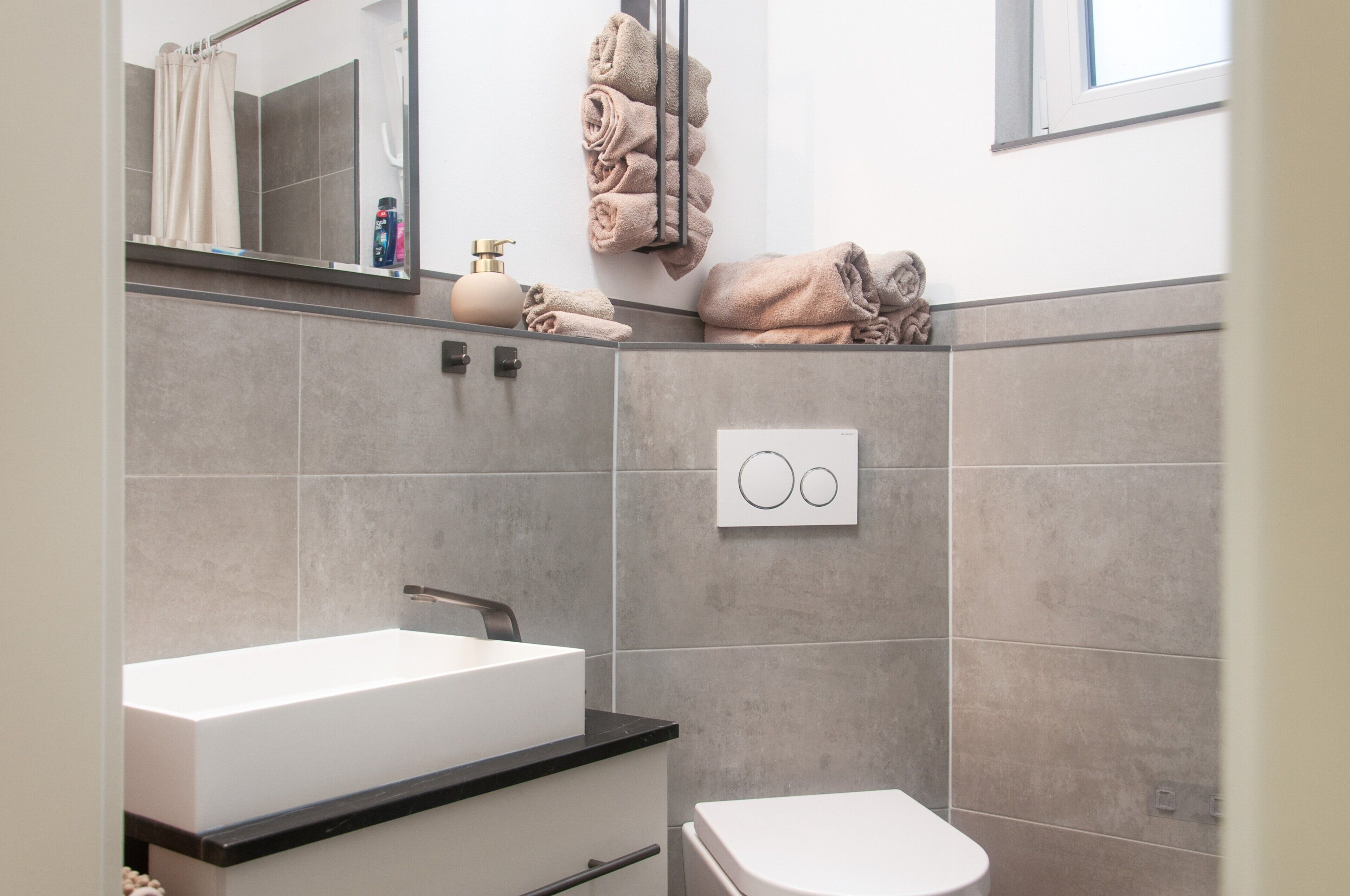 A modern bathroom with a white sink, a toilet, and a towel rack with folded towels.