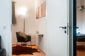 A room with a desk, chair, and a hanging light fixture.