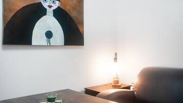 Et værelse med et maleri på væggen, et bord med stearinlys og en lampe på et sengebord.