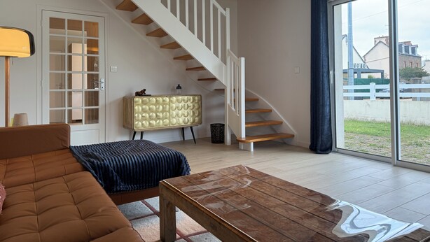 Una sala de estar moderna con una escalera, un sofá, una mesa de centro y un aparador.