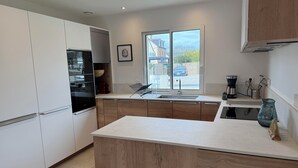 Una cocina moderna con una isla grande, horno empotrado y ventana con vistas al exterior.
