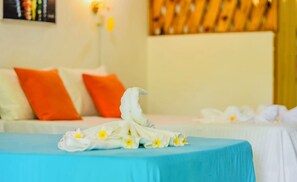 Ein Hotelzimmer mit einem Bett, Kissen, einem Handtuch und einer Wand mit einer Leuchte.