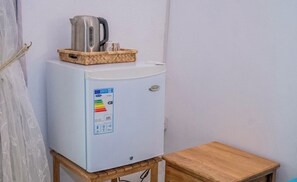 Un refrigerador compacto con pantalla digital, sobre una mesa de madera frente a una pared lisa.