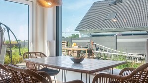 Un comedor moderno con sillas de mimbre, una mesa y una lámpara colgante.
