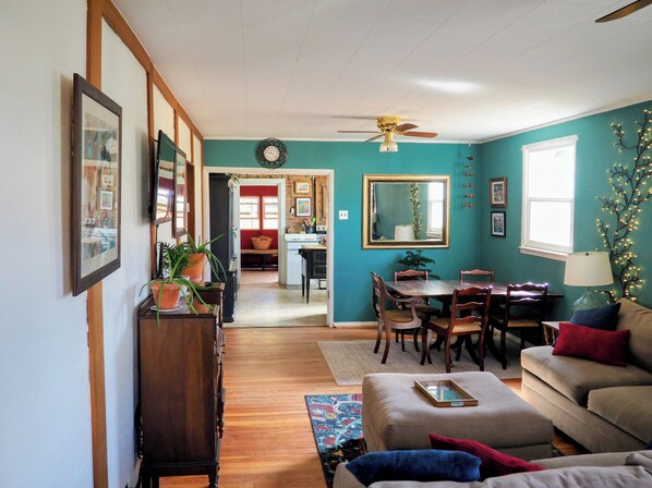 A cozy living room with a dining area, wooden furniture, a ceiling fan, and a large mirror.