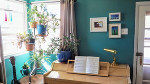 Ein Zimmer mit einem Klavier, einer Gitarre und mehreren Blumentöpfen.