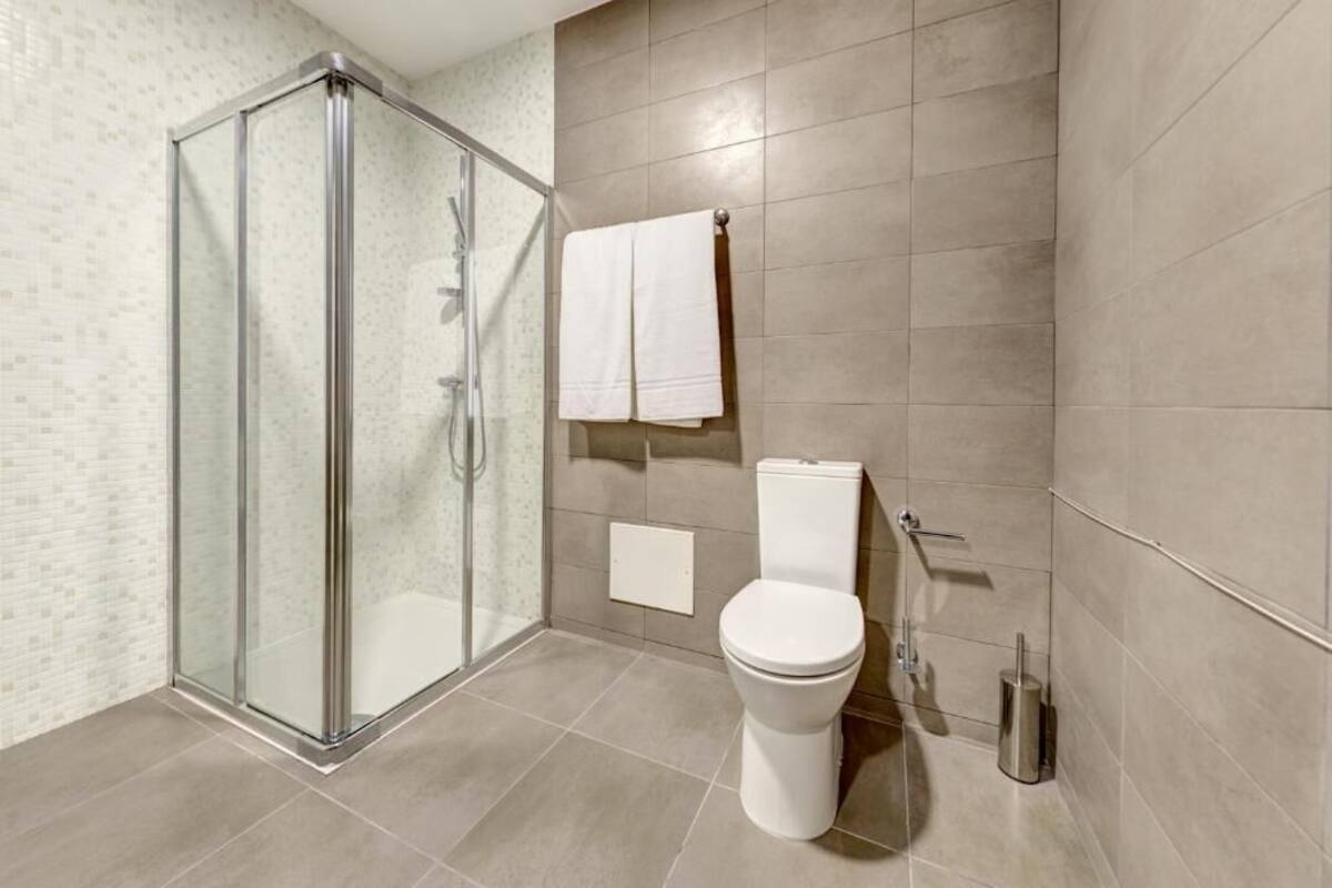 A modern bathroom with a glass shower enclosure, a toilet, and a towel rack.