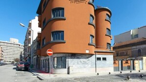 Ein mehrstöckiges Hotel mit einer geschwungenen Fassade und einem Schild, auf dem 'Hotel de Mercado' steht.