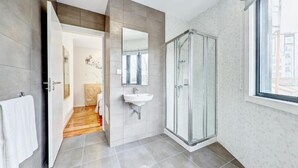 Ein modernes Badezimmer mit Dusche aus Glas, Waschbecken und großem Spiegel.