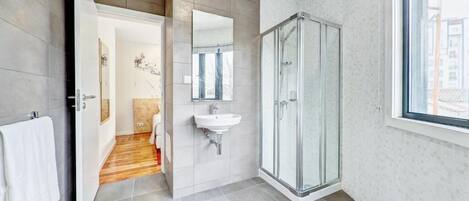 A modern bathroom with a glass shower, a sink, and a large mirror.