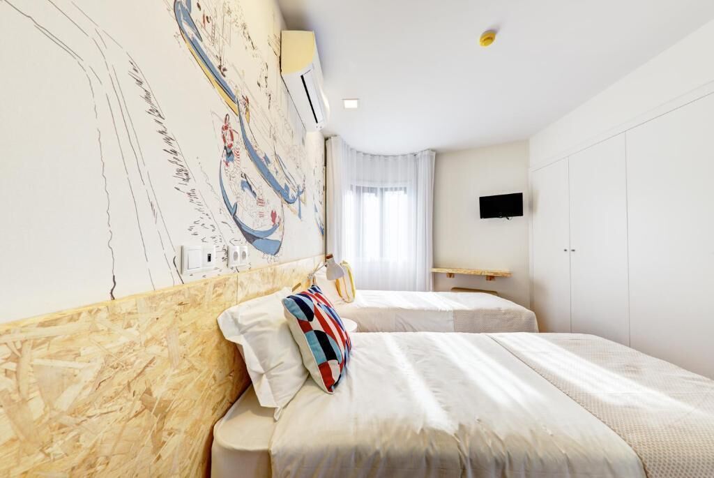 A hotel room with two beds, a large abstract painting on the wall, a flat-screen TV, and a window with curtains.