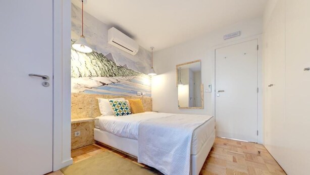 Ein Schlafzimmer mit einem Bett, einer Wand-Klimaanlage, einem Spiegel und einer Tür.