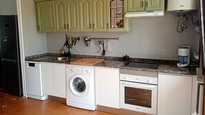 A kitchen with green cabinets, a washing machine, a stove, and a coffee maker. - House by the sea in the most beautiful village of Asturias!!! (Muros de Nalón)